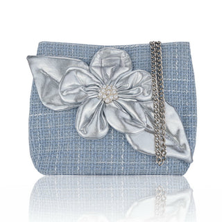 Blue crossbody bag with a large silver flower and chain strap on a white background
