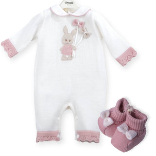 White romper by Bimbalo for babies it has purple ridged cuffs with a rabbit appliqué holding bow hearts in the centre it buttons up from the back. It’s matched with coordernating purple boots with 3D bows.