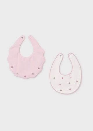 Two pink baby bibs with polka dot patterns on a light gray background