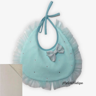 Cream cotton bib for baby girls by Petit Italia, it has a cream tulle rim around the edge scattered crystals across, and a silver bow in the corner. It is a lace fastening